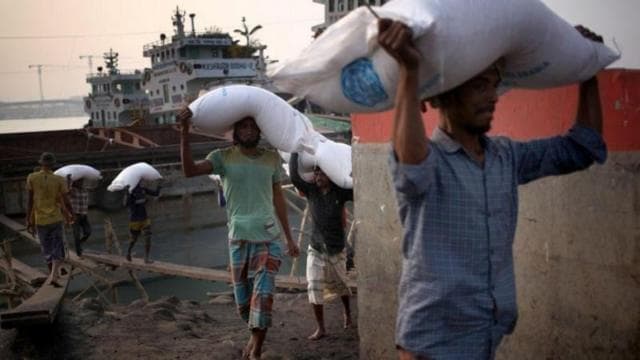 মাথায় করে সারের বস্তা নিয়ে যাচ্ছেন কয়েকজন শ্রমিক