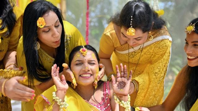 ভারতীয় কনের পরিবারের নারী সদস্য ও বান্ধবীরা তাকে ঘিরে ‘হলুদ’ অনুষ্ঠানের সময় গায়ে হলুদের প্রলেপ লাগাচ্ছেন। নারীরা উজ্জ্বল হলুদ রঙের শাড়ি পরে আছেন; তাদের কপালে হলুদ রঙের অলংকার এবং হাতে মেহেদি লাগানো।