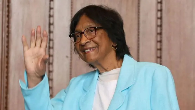 Navi Pillay reacts to receiving the prize in Nuremberg, Germany. She is wearing a sky blue jacket and standing against a wood panelled background